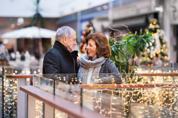 Senior couple doing Christmas shopping. Shopping center at Christmas time.