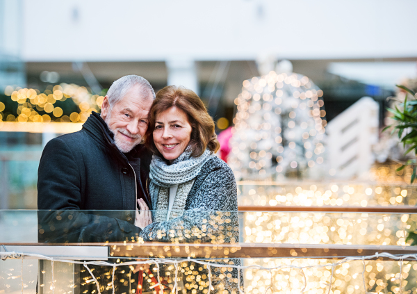 Senior couple doing Christmas shopping. Shopping center at Christmas time.