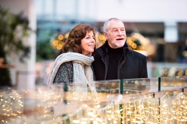 Senior couple doing Christmas shopping. Shopping center at Christmas time.