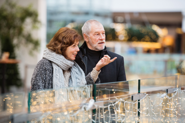 Senior couple doing Christmas shopping. Shopping center at Christmas time.