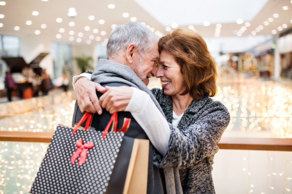 Senior couple doing Christmas shopping. Shopping center at Christmas time.