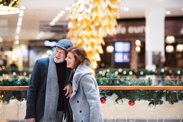 Senior couple doing Christmas shopping. Shopping center at Christmas time.