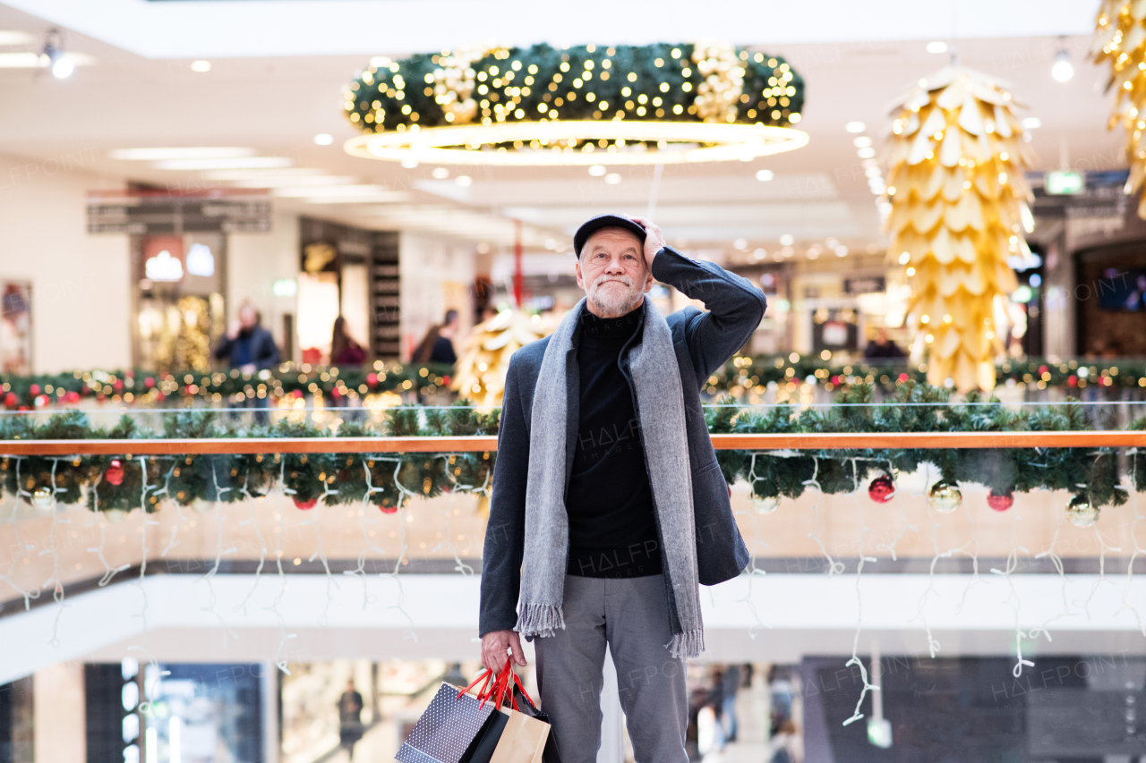 Senior man doing Christmas shopping. Shopping center at Christmas time.