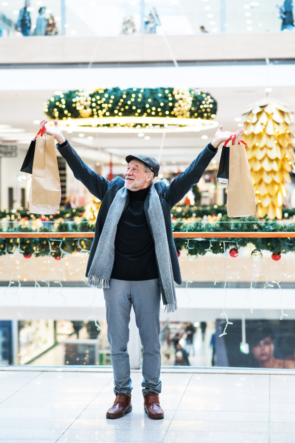 Senior man doing Christmas shopping. Shopping center at Christmas time.