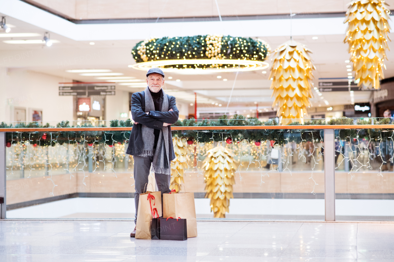 Senior man doing Christmas shopping. Shopping center at Christmas time.