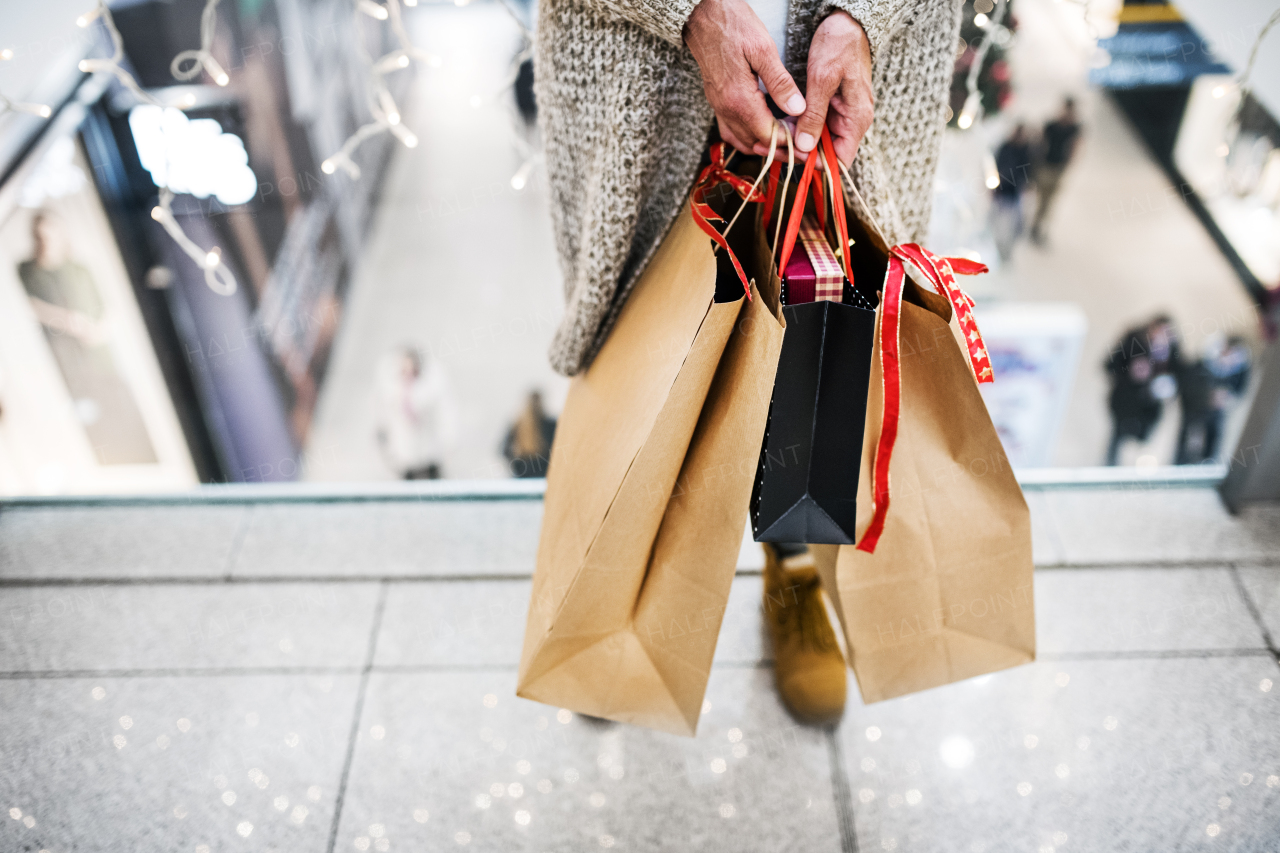 Unrecognizable senior woman with paper bags doing Christmas shopping. Shopping center at Christmas time.