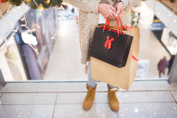 Unrecognizable senior woman with paper bags doing Christmas shopping. Shopping center at Christmas time.