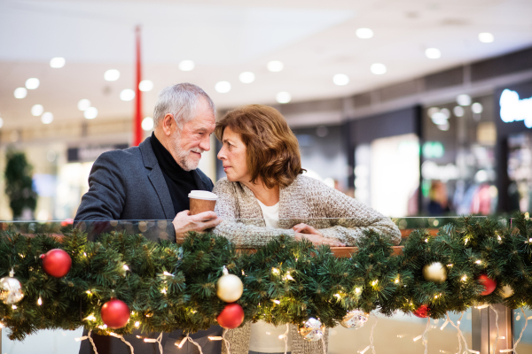 Senior couple doing Christmas shopping. Shopping center at Christmas time.