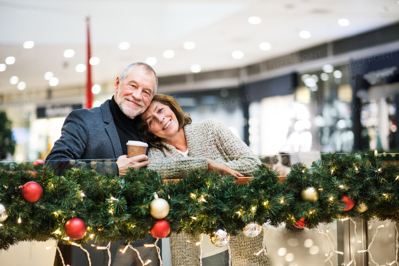 Senior couple doing Christmas shopping. Shopping center at Christmas time.