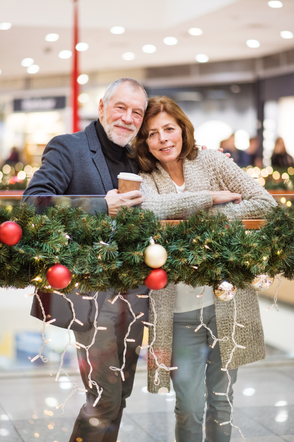 Senior couple doing Christmas shopping. Shopping center at Christmas time.