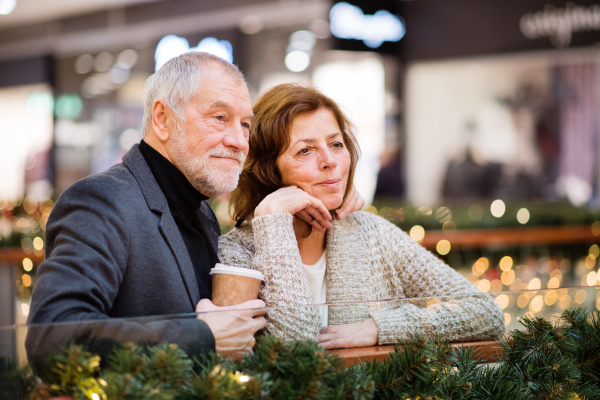 Senior couple doing Christmas shopping. Shopping center at Christmas time.