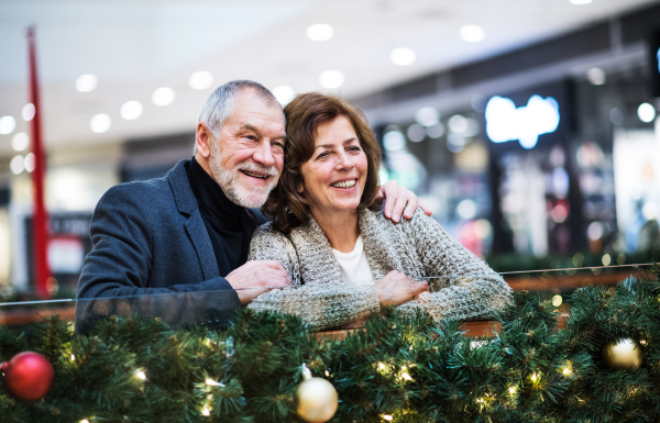 A portrait of happy senior couple in shopping center at Christmas time.