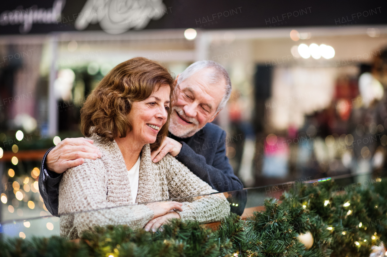 Senior couple doing Christmas shopping. Shopping center at Christmas time.