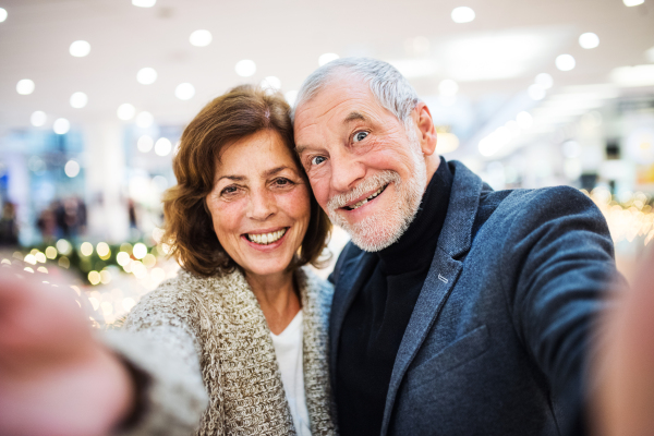 Happy senior couple taking selfie in shopping center at Christmas time.