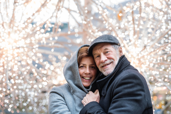 A portrait of senior couple standing outdoors in front of shopping center at Christmas time. Copy space.