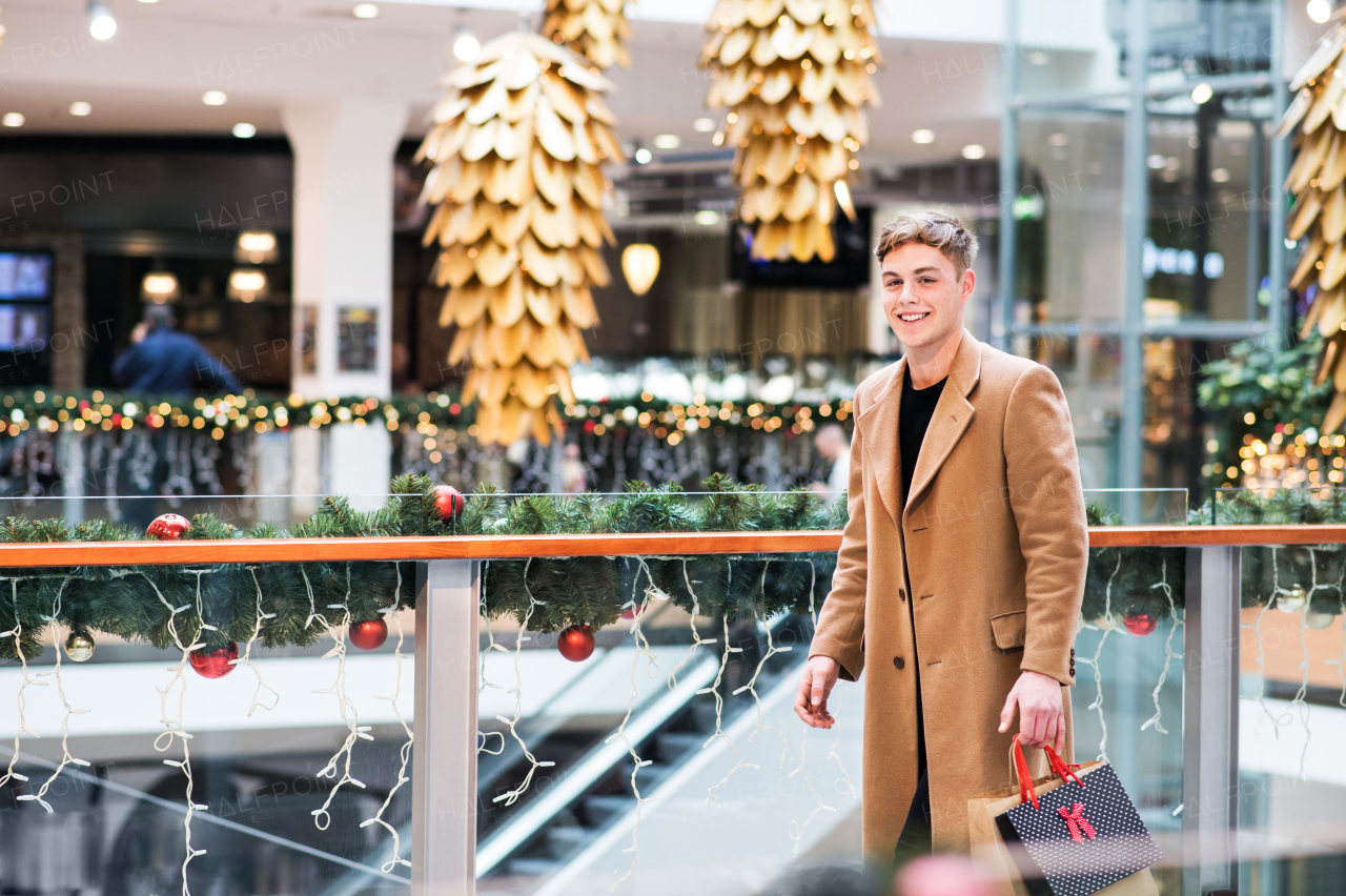 A portrait of teenage boy walking in shopping center at Christmas. Copy space.