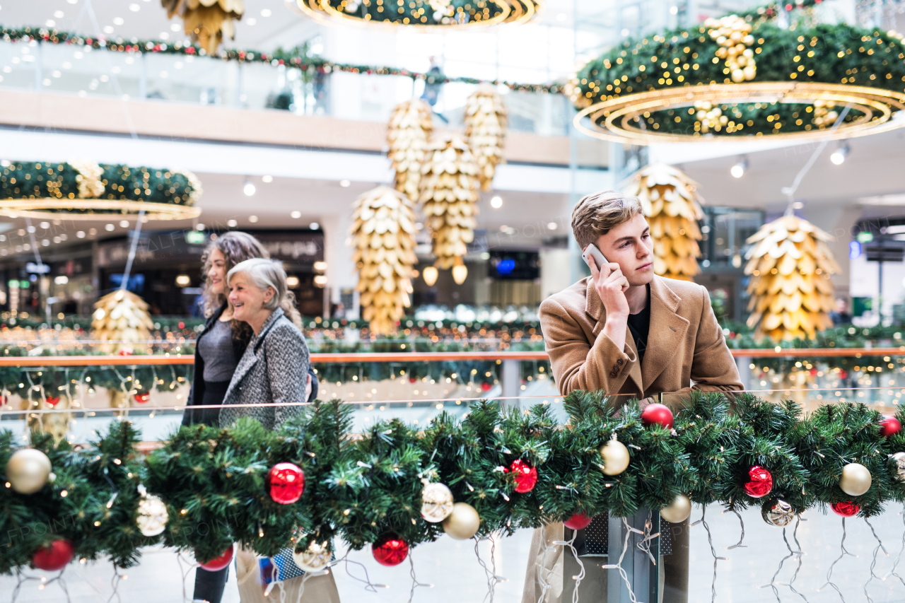 A portrait of teenage boy with smartphone in shopping center at Christmas, making a phone call.