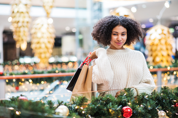 A portrait of happy teenage girl with paper bags in shopping center at Christmas.