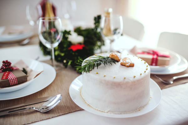 A white cake on a table set for dinner at home at Christmas time.