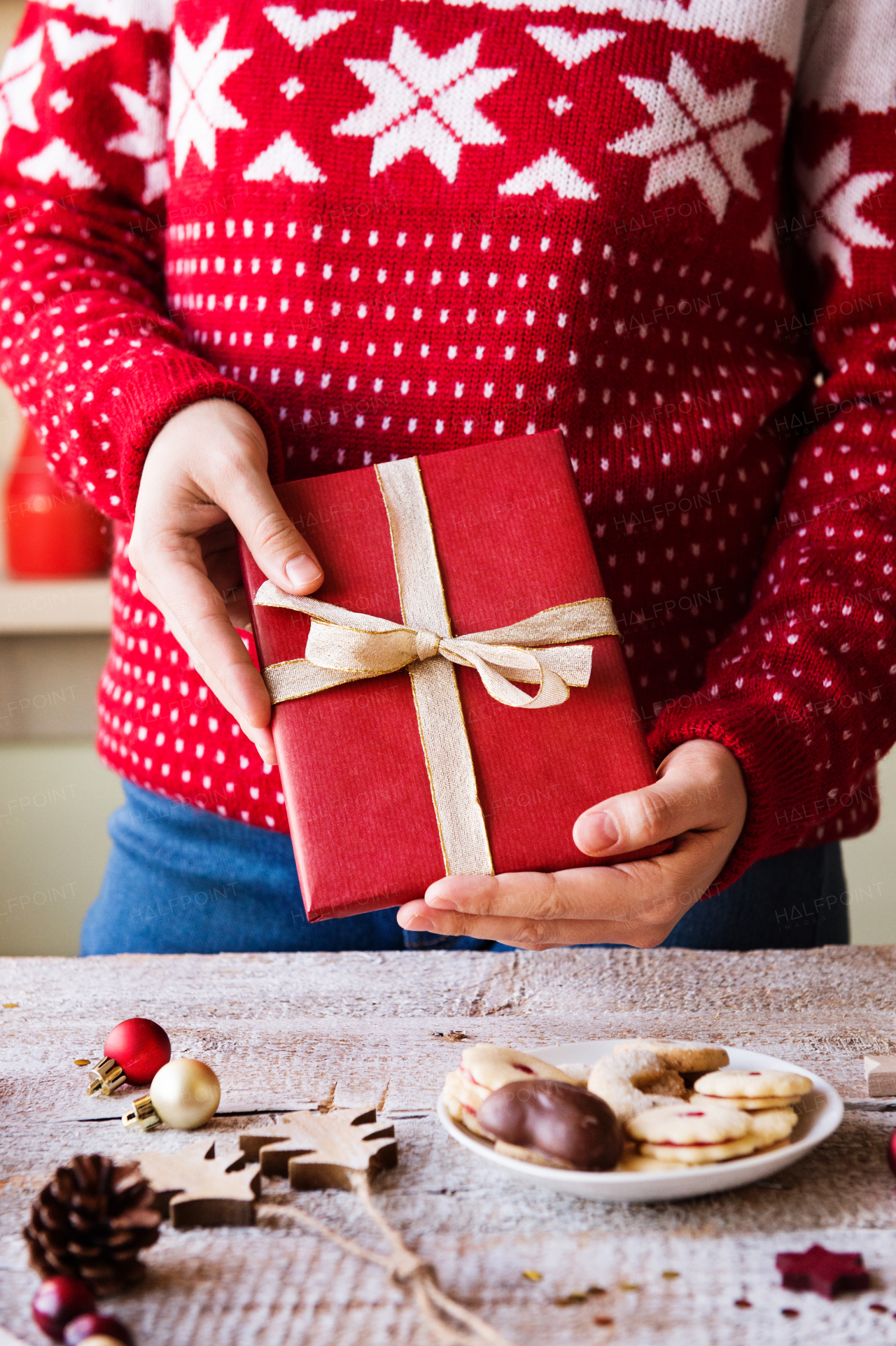 Christmas composition on a vintage wooden background. Unrecognizable woman holding a Christmas present.