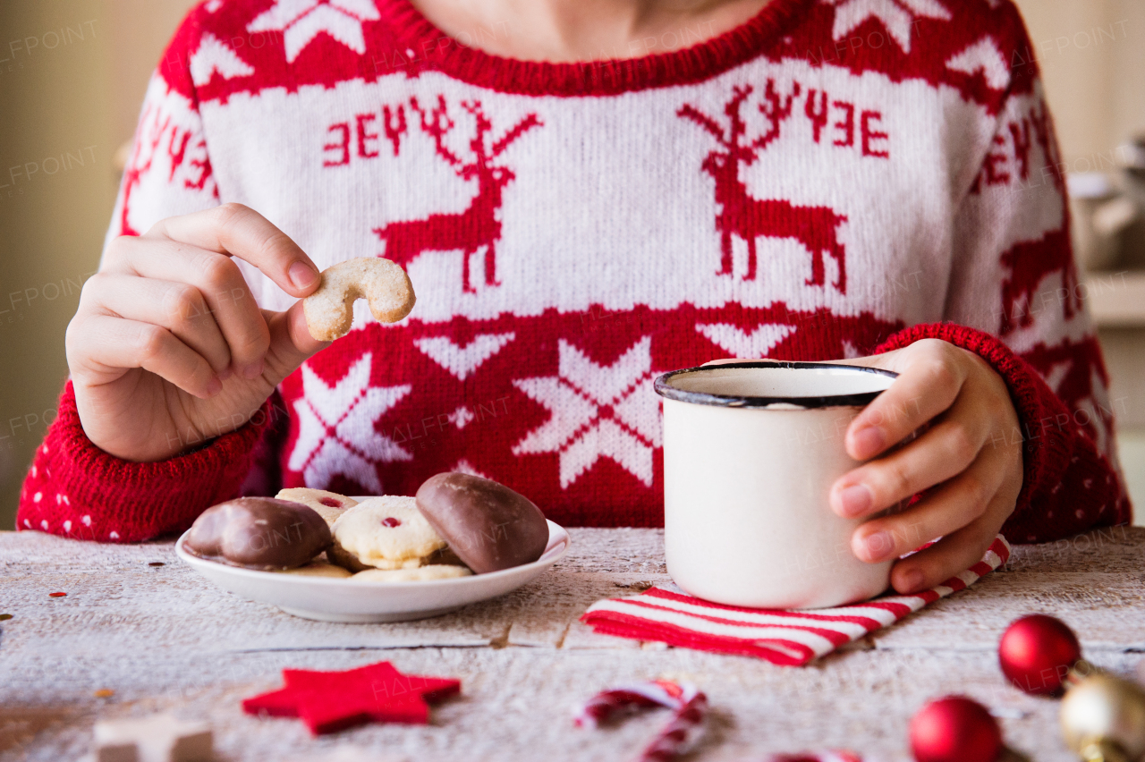 Christmas composition on a vintage wooden background. Unrecognizable woman eating biscuits and drinking coffee.