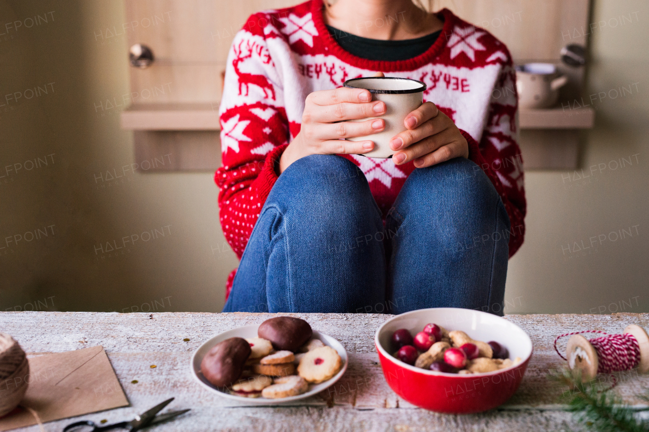 Unrecognizable woman sitting and drinking coffee at Christmas time.