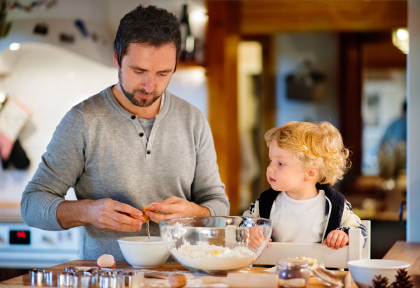 Man and toddler boy making cookies at home. Father and son baking gingerbread Christmas cookies.