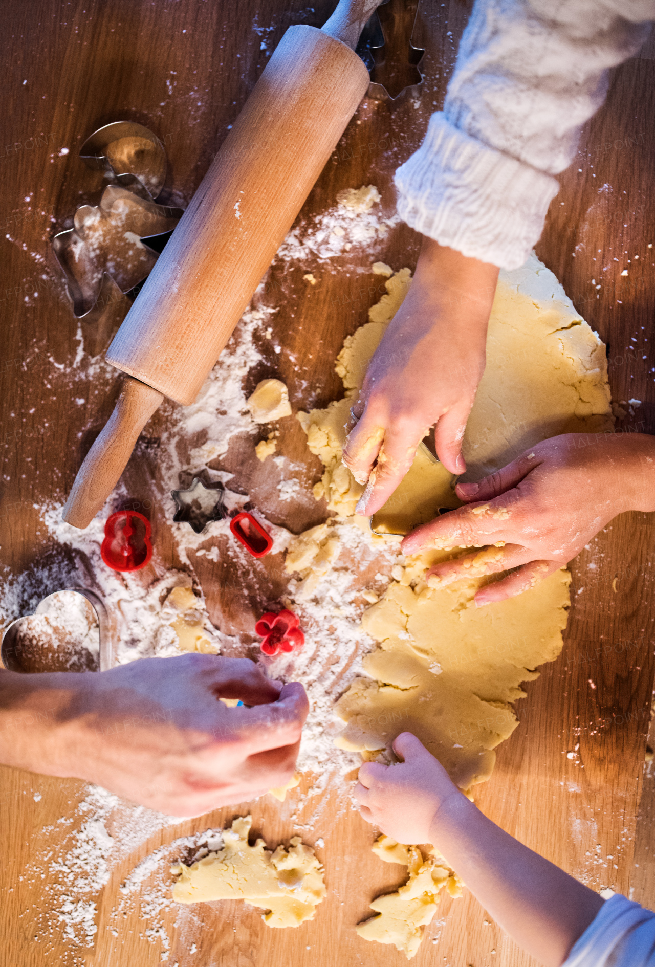 Unrecognizable woman, man and toddler child making cookies at home. Hands of father, mother and son baking gingerbread Christmas cookies. Close up.