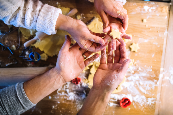 Unrecognizable woman, man and toddler child making cookies at home. hands of father, mother and son baking gingerbread Christmas cookies. Close up.