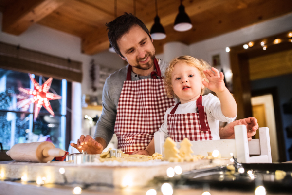 Man and toddler boy making cookies at home. Father and son baking gingerbread Christmas cookies.