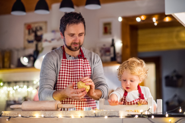 Man and toddler boy making cookies at home. Father and son baking gingerbread Christmas cookies.