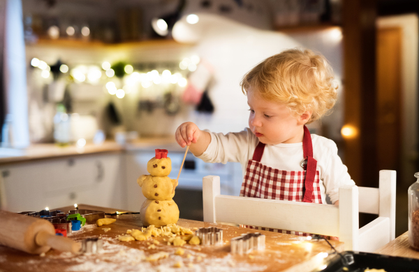 Toddler boy making gingerbread cookies at home. Christmas time.