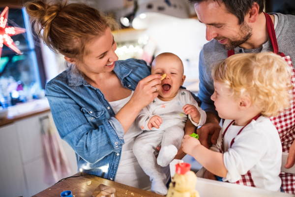 Beautiful young family making cookies at home. Father, mother. toddler boy and baby having fun.