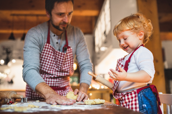 Man and toddler boy making cookies at home. Father and son baking gingerbread Christmas cookies.