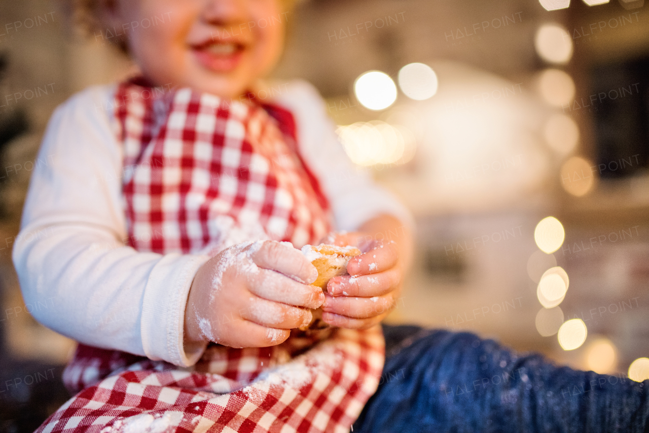 Unrecognizable toddler boy making gingerbread cookies at home. Little boy sitting on the table. Christmas time. Close up.