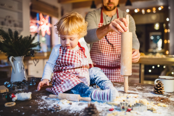 Man and toddler boy making cookies at home. Father and son baking gingerbread Christmas cookies.