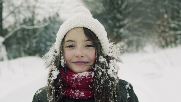 Portrait of a small girl standing in winter nature, having fun. Close up.