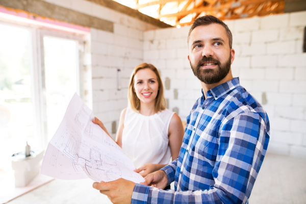 Young couple at the construction site. A man and woman looking at plans of the new house, discussing issues at the construction site.