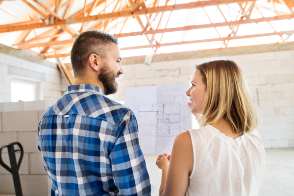 Young couple at the construction site. A man and woman looking at plans of the new house, discussing issues at the construction site.