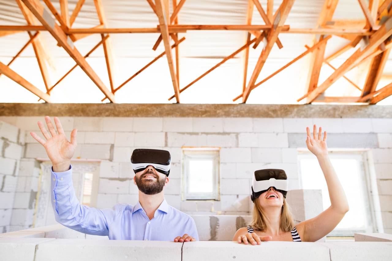 Young married couple or architects with virtual reality goggles at the construction site.