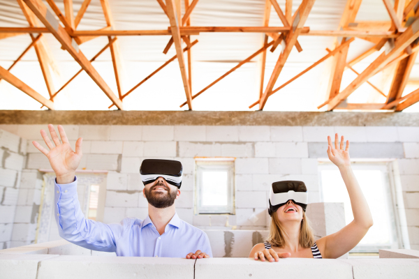 Young married couple or architects with virtual reality goggles at the construction site.