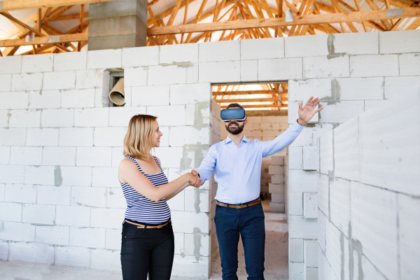 Young married couple or architects with virtual reality goggles at the construction site.