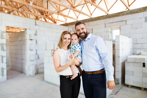 Young happy couple with a baby boy at the construction site.