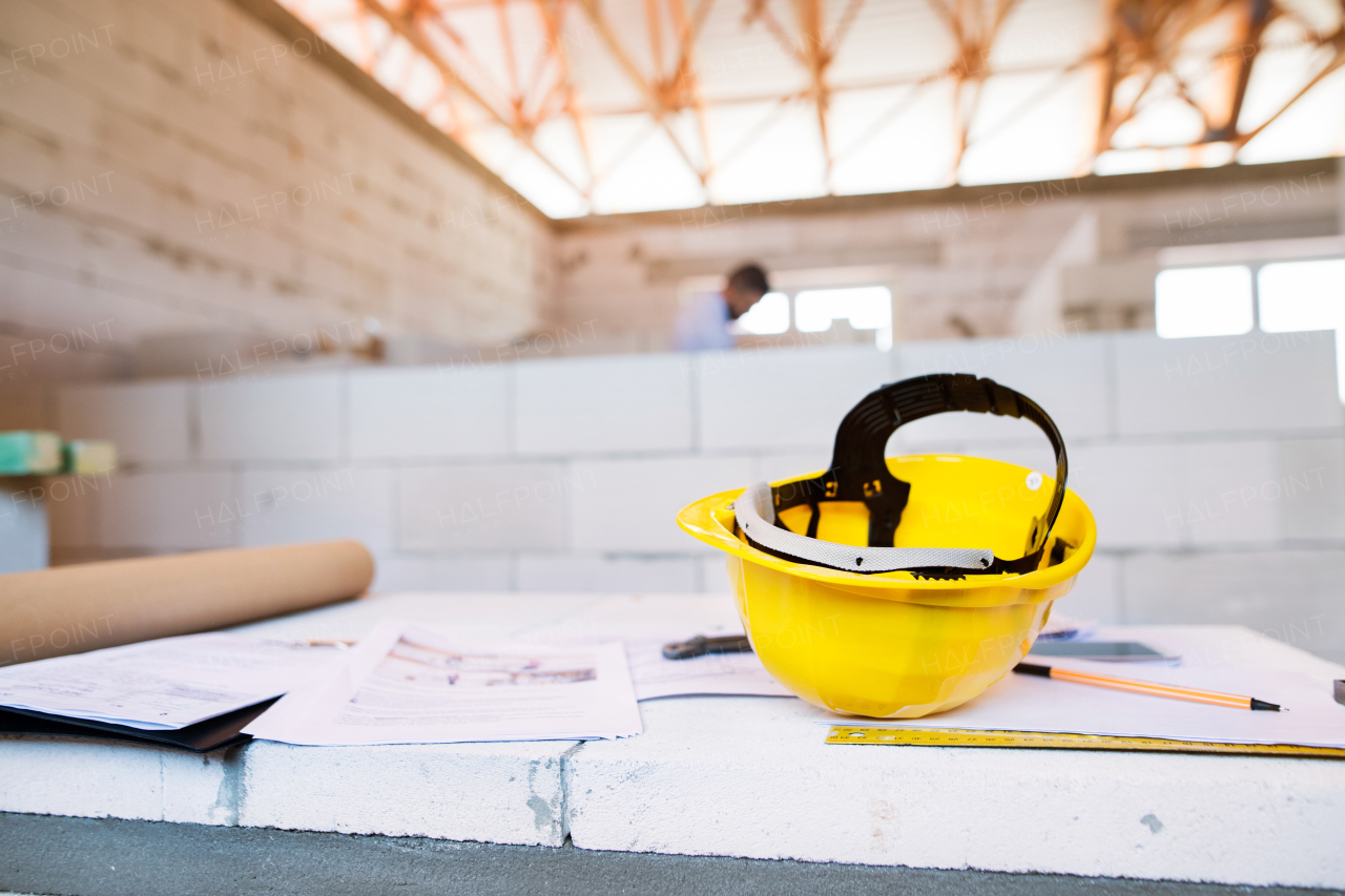 Close up of helmet, blueprints and other equipment on construction site