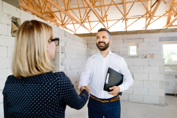 Architect and civil engineer shaking hands at the construction site.