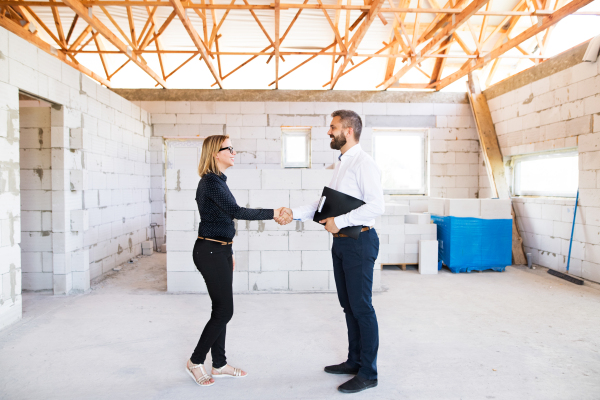 Architect and civil engineer shaking hands at the construction site.