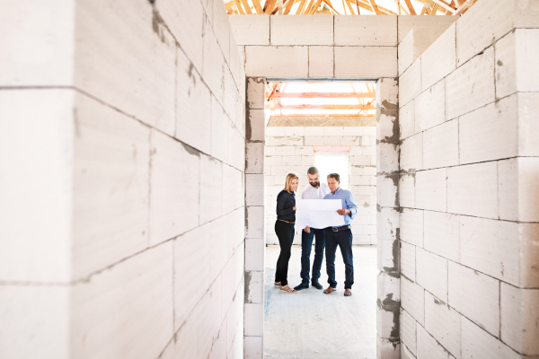 Architects and civil engineer looking at plans and blueprints, discussing issues at the construction site.