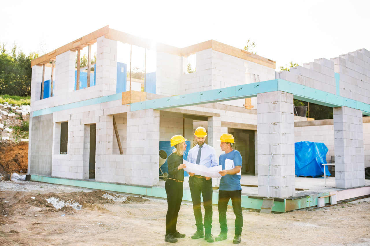 Architect, civil engineer and worker looking at plans and blueprints, discussing issues at the construction site.