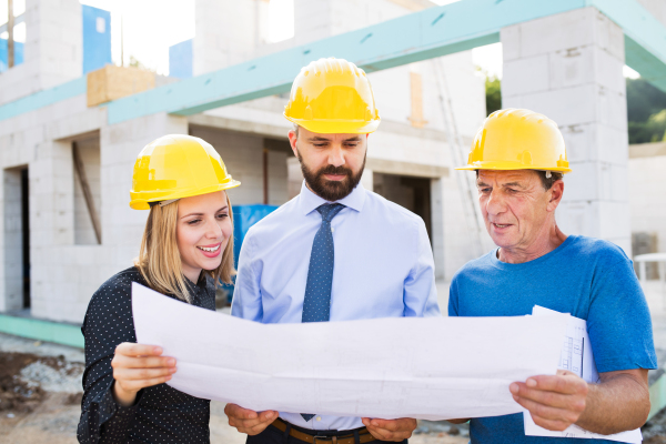 Architect, civil engineer and worker looking at plans and blueprints, discussing issues at the construction site.