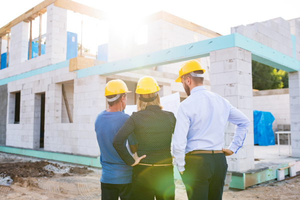 Architect, civil engineer and worker looking at plans and blueprints, discussing issues at the construction site.